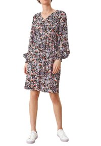 Kukka-aiheinen mekko mustalla taustalla, jossa on purple, pinkki ja oranssi kukkia. Pitkät hihat, v-kaula-aukko ja rento malli. Yhdistetty valkoisiin lenkkareihin.