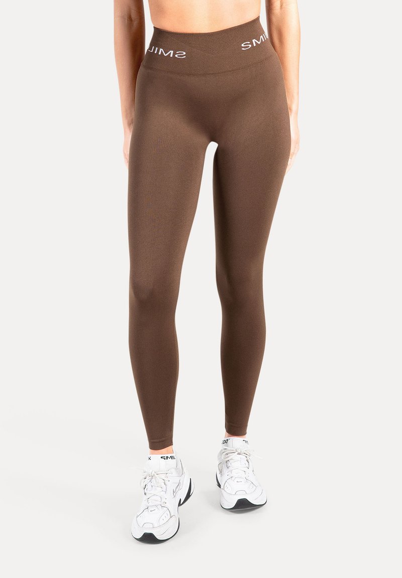 Leggings marrones de cintura alta hechos de tela elástica con textura suave; cuentan con una banda blanca con logo en la cintura. Adecuados para ropa deportiva.