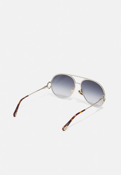 Óculos de sol aviador em metal com lentes cinza degradê, apresentando armações em tom dourado e detalhes em tortoiseshell castanho nos braços das hastes.