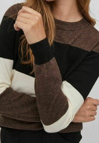 Stickad tröja med svarta, bruna och krämfärgade horisontella ränder. Har rund halsringning och ribbade ärmslut. Mjukt material, avslappnad passform.