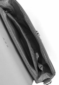 Šedá kabelka s hladkým povrchem, uvnitř s motivem v zig-zag vzoru, má zipovou kapsu a lesklé kovové akcenty.