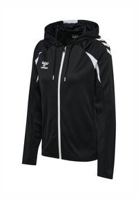 Veste noire à capuche zippée avec des accents blancs sur les épaules et les côtés, avec le logo hummel sur la poitrine et des motifs en chevrons sur l'épaule droite.