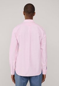 Chemise rayée rose clair avec de longues manches et un col classique. Les détails notables incluent des poignets à boutons et un ourlet légèrement arrondi.