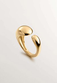 Anillo abierto dorado con un diseño suave y redondeado, que presenta dos extremos abultados que se estrechan hacia la banda, creando un aspecto contemporáneo.