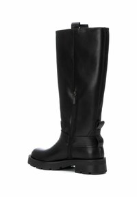 Botas de cuero negras hasta la rodilla con un cierre lateral, punta redonda y suela de goma gruesa. Cuenta con una tira en la parte superior para facilitar su calzado.