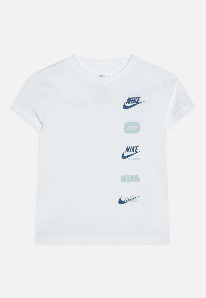 Camiseta de algodón blanca con varios logotipos de Nike en azul oscuro y azul claro, mostrados verticalmente en la parte delantera. Manga corta y cuello redondo.