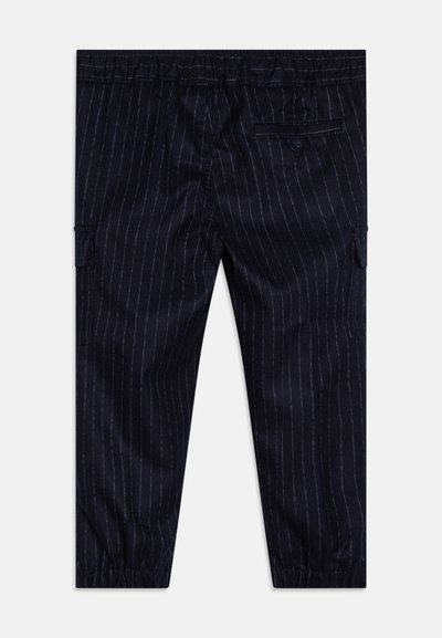 Pantaloni blu navy con righe verticali bianche, vita elasticizzata, tasche laterali e una tasca posteriore con bottone. Tessuto liscio.
