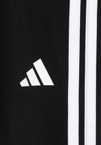 Schwarzer Sportstoff mit drei vertikalen weißen Streifen und einem weißen adidas-Logo, mit glatter Textur und regulärem Schnitt.