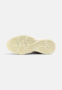 Suela de zapatilla con una superficie de goma texturizada, que presenta un patrón de picos en amarillo claro, diseñada para ofrecer tracción y agarre.