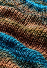Strickstoff mit abwechselnden Streifen in Braun, Blau und Teal, der ein strukturiertes Muster mit dicker, fusseliger Wolle aufweist.