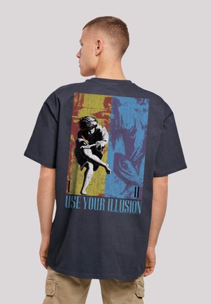 Navy cotton t-shirt featuring a large graphic print on the back with colorful blocks, text "USE YOUR ILLUSION," and a stylized figure.