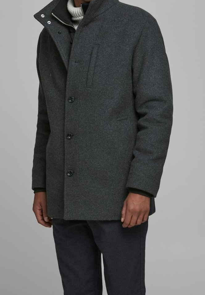 Cappotto di lana grigio con colletto alto, dotato di chiusura a zip e una tasca sul petto. Chiusura frontale con bottoni, vestibilità rilassata e texture morbida.