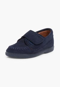 Mocassin en daim bleu marine avec une sangle Velcro, bout arrondi et couture décorative le long du bord. Semelle en caoutchouc plate.