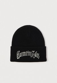 Bonnet en tricot noir avec revers, brodé en blanc dans une police Old English avec l'inscription "Commuting Tales" sur le devant.