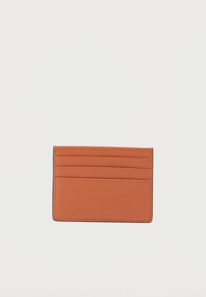 Oransje skinn kortholder med flere lommer, glatt tekstur og subtil preget logo. Kompakt og rektangulært design.