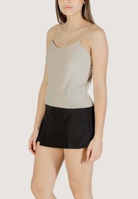 Canottiera a coste grigia chiara con spalline a catena sottili, abbinata a un fondo svasato nero. Tessuto morbido con colori e silhouette a contrasto.