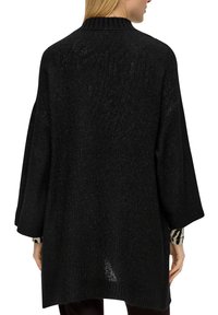 Schwarzer übergroßer gestrickter Pullover mit Dreiviertelärmeln und geripptem Kragen. Strukturierter Stoff mit leichtem Glanz.