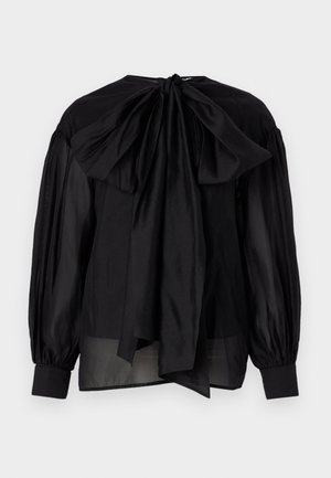 Blusa nera in tessuto trasparente, con maniche a sbuffo e un grande fiocco sul retro. Presenta un colletto rotondo e polsini aderenti.