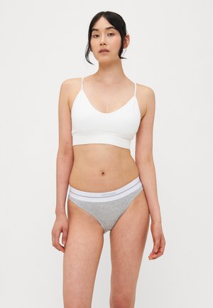 Soutien-gorge de sport blanc à côtes avec des fines bretelles et un string gris avec une ceinture élastique blanche. Conception simple et ajustée.