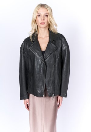 Chaqueta de motociclista de cuero negro con un acabado texturizado, cuello con muesca y cremallera asimétrica, combinada con una falda de satén rosa claro.