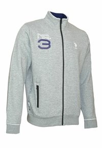 Felpa grigia con zip e colletto alto, caratterizzata da una grafica viola "NR. 3" e un logo polo. Include una tasca laterale con zip e polsini a coste.