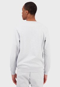 Sudadera gris con cuello redondo, mangas largas y puños acanalados. Textura suave similar al algodón, ligero estiramiento y un ajuste casual.