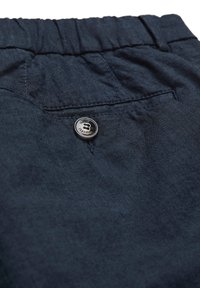 Pantalon en tissu bleu foncé avec une taille élastique et une poche arrière sécurisée par un seul bouton.