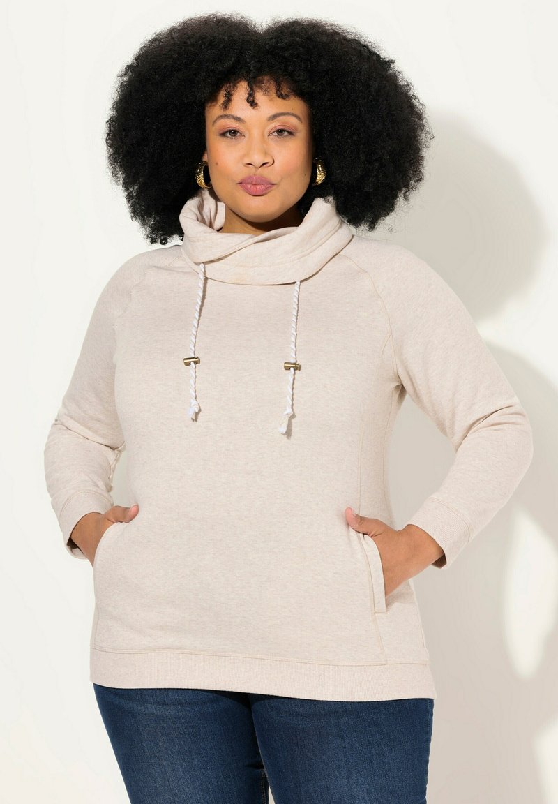 Hoodie con collo a cappuccio in beige chiaro, realizzato in tessuto morbido. Presenta cordini con accessori dorati, maniche lunghe e tasche laterali.