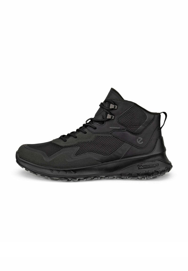 Scarpe da trekking nere impermeabili, di altezza media, con una superficie testurizzata, chiusura con lacci e suola in gomma Michelin per una buona aderenza.