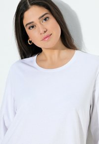 Witte lange mouwen katoenen T-shirt met een ronde halslijn, een gladde textuur en een losse pasvorm. Eenvoudig ontwerp, geen zichtbare patronen of accenten.