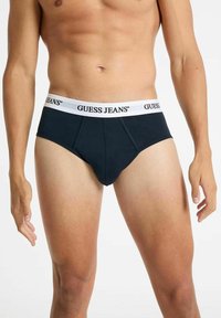 Mutande in cotone nero con un elastico bianco sulla vita con la scritta "GUESS JEANS". Presentano una parte anteriore sagomata e un taglio standard.