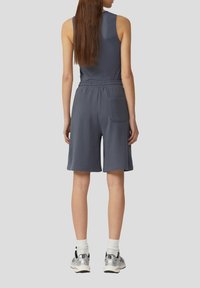 Grijze mouwloze top met een geribbelde textuur, gecombineerd met bijpassende short met trekkoord. Voorzien van een achterzak en zijsplitten aan de zoom.