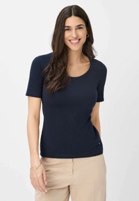 Mørkeblå kortærmet t-shirt lavet af blødt bomuld, med en rund halsudskæring og en tætsiddende pasform, parret med beige bukser.