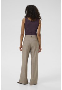 Pantalons taille haute, à jambes larges en tweed marron clair, avec deux poches arrière. Associés à un débardeur ajusté en rib de couleur violette.