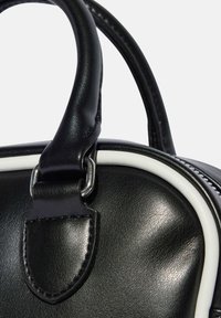 Black leather handbag features a rounded shape with a white trim, metal hardware, and a textured surface. Handles attached with sleek silver accents.