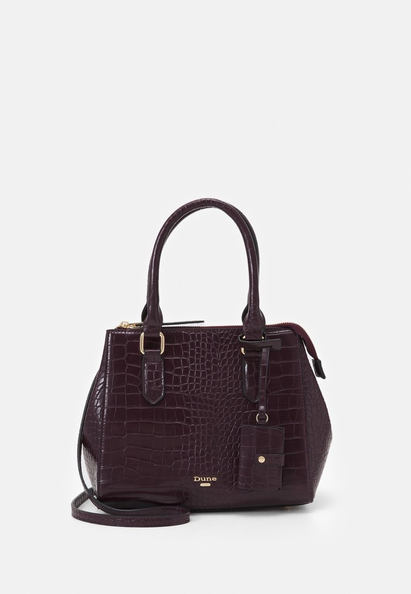 Torebka w kolorze burgundowym o fakturze krokodylej, z solidnymi podwójnymi uchwytami, odpinanym paskiem na ramię, złotymi akcentami i małą przypinaną metką.