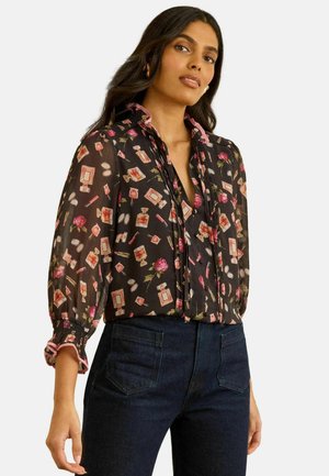 Svart blommig blus med en volangkrage, med ett mönster av kosmetika och blommor. Långa ärmar med rynkade muddar och rosa detaljer.
