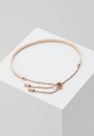 Dunne verstelbare roségouden bangle armband met een gladde band en twee hangende kettingeinden op een witte ondergrond.