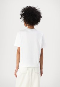 Tricou alb cu mânecă scurtă, având un design simplu și clasic, cu un guler rotund. Țesătură netedă; vista din spate arată un stil simplu, fără grafică.
