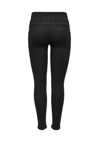 Leggings de mezclilla negra con una cinturilla alta de textura acanalada, dos bolsillos traseros y un ajuste slim que se extiende hasta el tobillo.