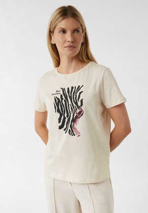 T-shirt en coton couleur crème avec un col rond, présentant un design graphique noir et rose ainsi que du texte, conçu avec des manches courtes.