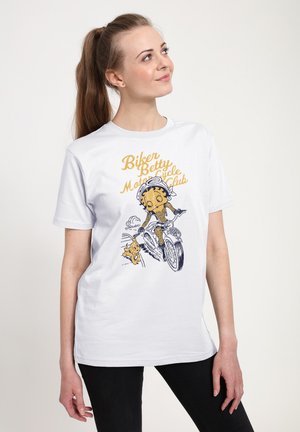Hvid t-shirt med et grafisk design af en karakter, der cykler, ledsaget af en lille hund. Teksten siger "Biker Betty Motorcycle Club."