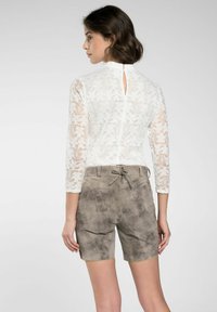 Tunique en dentelle blanche avec des manches trois-quarts et un dos en forme de clé; short en suède gris avec taille à cordon et accents sur les côtés.