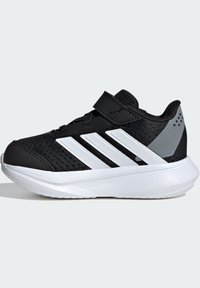 Scarpe da ginnastica nere con tomaia in mesh, design a tre strisce bianche e una fascia con chiusura a strappo. Presentano una suola leggera e dettagli grigi.