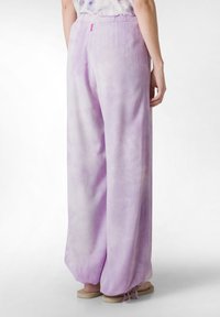 Ljuslila vida byxor i en mjuk, flytande tyg med ett subtilt tie-dye-mönster; har en elastisk midja och justerbar dragsko vid bensluten.