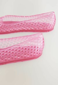 Růžové průhledné vložky do bot s mřížkovaným vzorem, s hladkým povrchem a zakulacenými okraji. Lehký a flexibilní design.