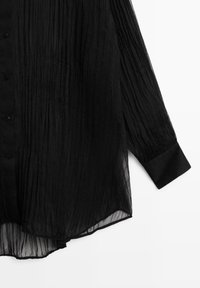 Blusa nera plissettata con maniche lunghe, chiusura con bottoni e orlo che si curva verso l'alto. Realizzata in tessuto trasparente e leggero.