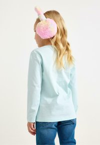 Vaaleanpunaiset ja keltaiset pehmeät korvaläpät, joissa on pupunkorvat. Vaaleansininen pitkähihainen paita ja siniset farkut. Lapsi kuvattu takaa.