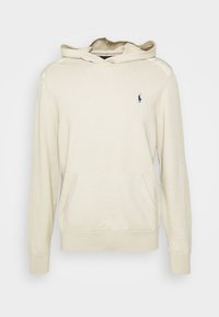 Sweat à capuche en coton beige à manches longues, poche kangourou à l'avant, poignets côtelés, et petit logo bleu marine sur la poitrine. Texture lisse, design simple.