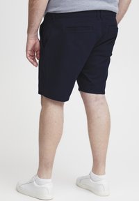 Marineblaue Shorts aus einem Baumwollmischgewebe, mit seitlichen und hinteren Taschen, geradem Schnitt und Länge über dem Knie.